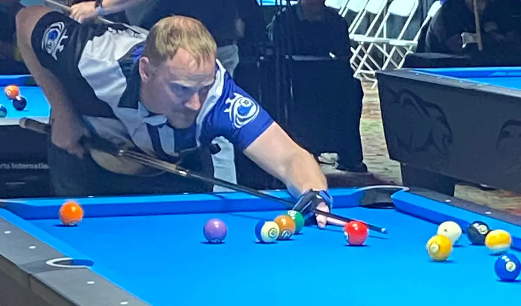 A player lines up a shot on a blue-cloth table during league play